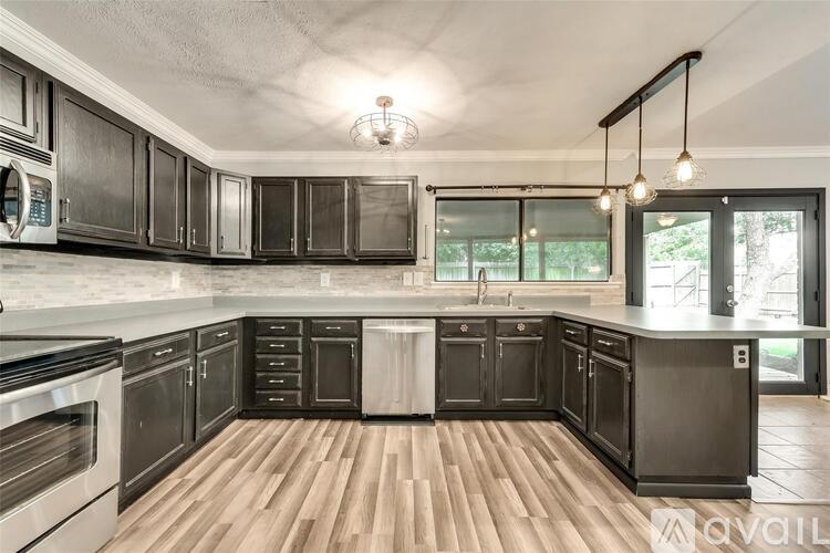 A kitchen with black cabinets and a wooden floor.