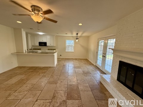A living room with a fireplace and a kitchen area in the background.