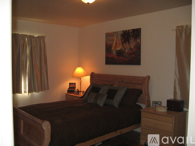 A bedroom with a bed, nightstand, and a painting on the wall.