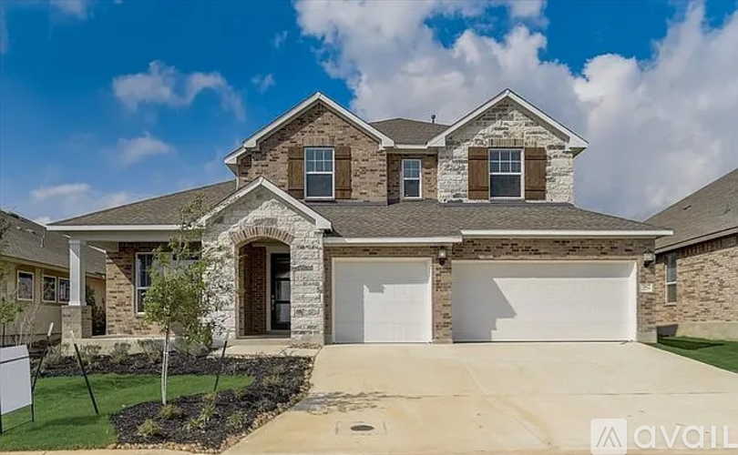 A house with a stone facade and a large driveway is for sale.