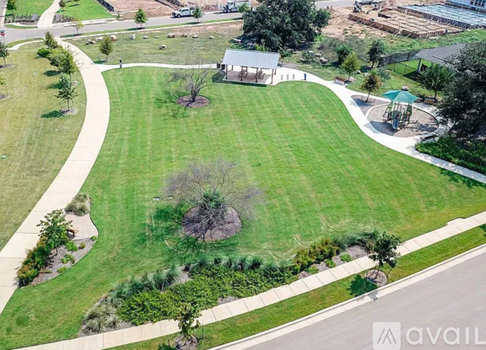 A grassy park with a walking path and a pavilion.