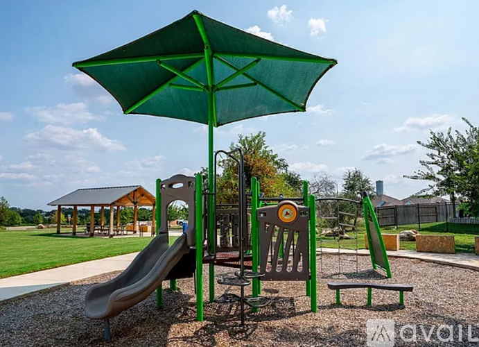 A playground with a green umbrella and slide.
