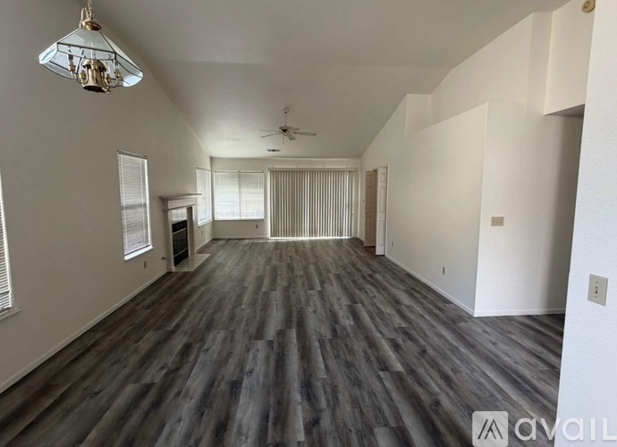 A spacious room with wood flooring and a ceiling fan.