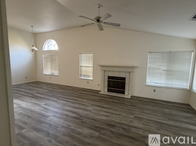 A spacious living room with a fireplace and a ceiling fan.