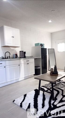 A modern kitchen with white cabinets and a black and white rug.