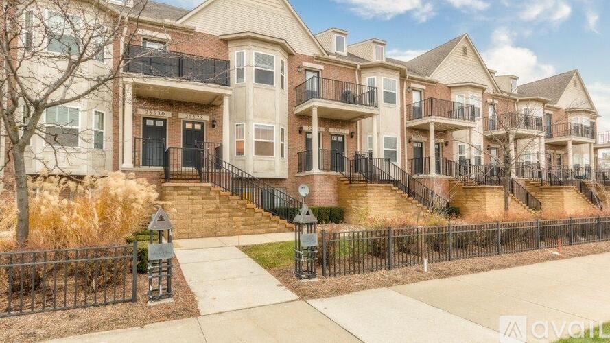 A row of townhouses with a black fence and a sidewalk in front.