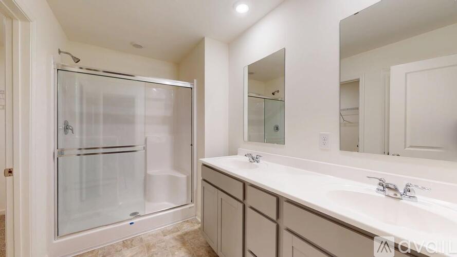 A bathroom with a walk-in shower and double sinks.