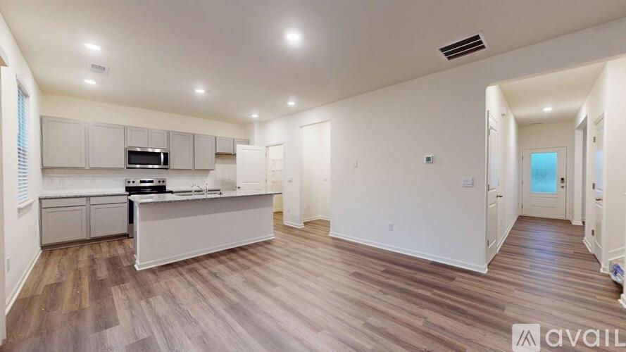 A spacious living room with wood flooring and white walls.