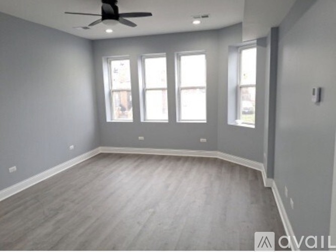 A spacious room with a ceiling fan and three windows.