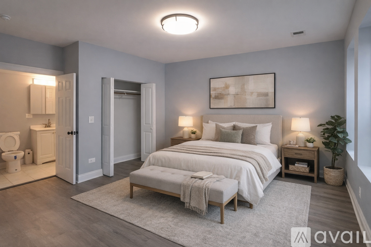 A bedroom with a large bed, a bench, and a plant.