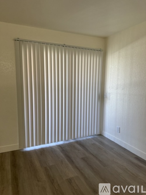 A room with a window covered by white blinds.
