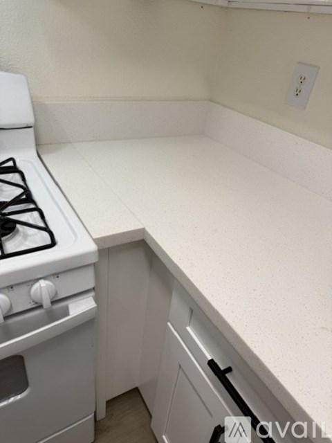 A white kitchen with a stove and a counter.