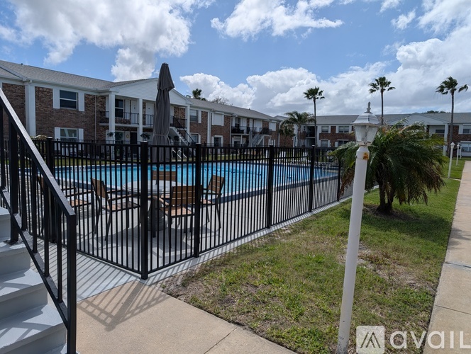 A pool surrounded by a black fence with a building in the background.