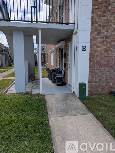 A white building with a black gate and a green trash can.