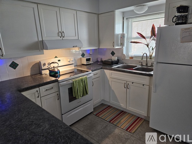 A kitchen with white cabinets and a black countertop.