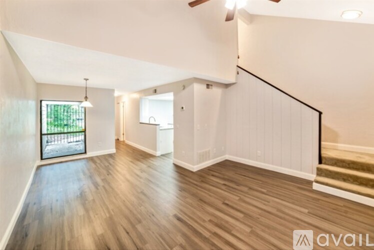 A spacious room with wooden flooring and a staircase leading to another level.
