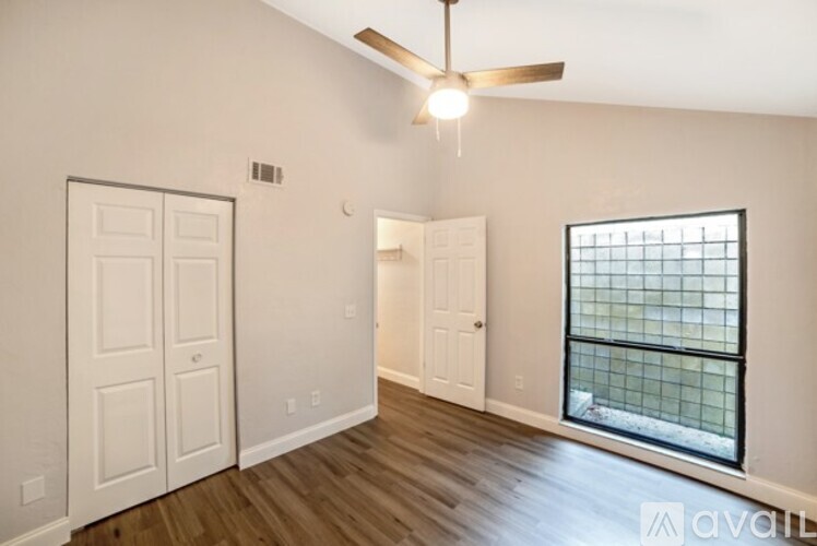 A room with a ceiling fan and a window with bars.