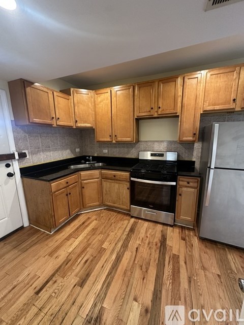 A kitchen with wooden cabinets and a stainless steel refrigerator.