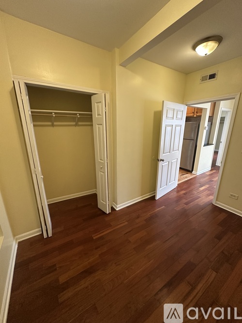 A room with a wooden floor and a white closet with a mirror.