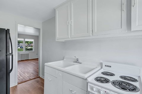 A white kitchen with a stove, sink, and refrigerator.