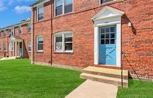 A red brick building with a blue door and a small porch.