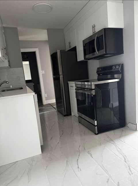 A modern kitchen with black appliances and white cabinets.