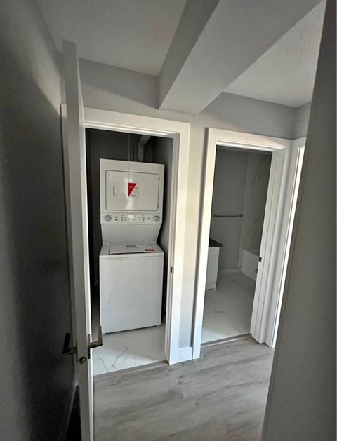 A white washing machine is in a small room with a door open.