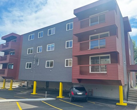 A car is parked in a parking lot in front of a two-story building.