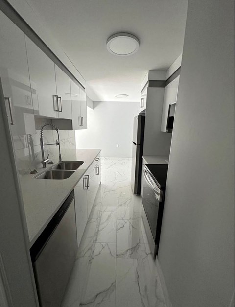 A modern kitchen with a marble floor and white cabinets.