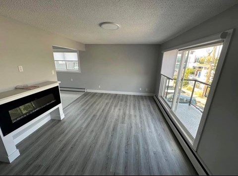 A room with a fireplace and a window overlooking a street.