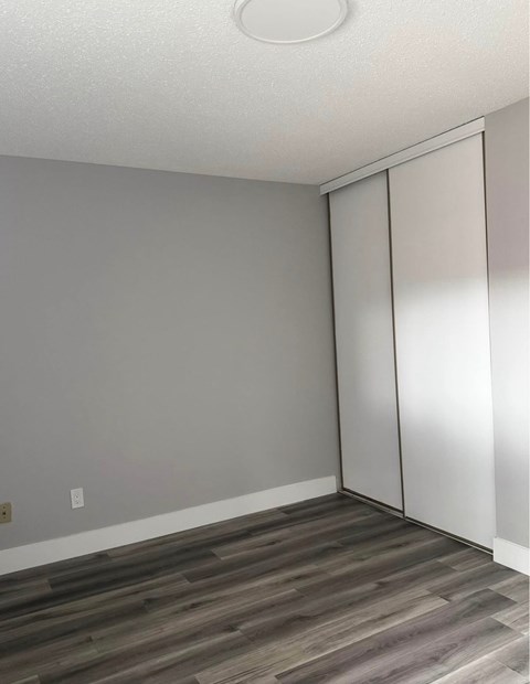 A room with a grey wall and a wooden floor with a white ceiling and a white door.