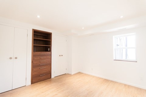 A room with a white wall and a brown wardrobe.