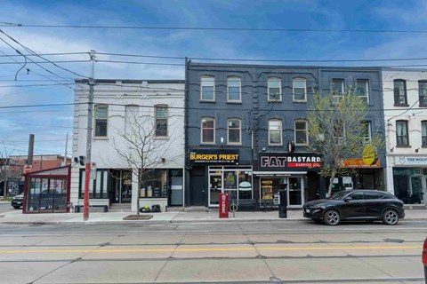 A black car is parked in front of a Burger's Pest restaurant.