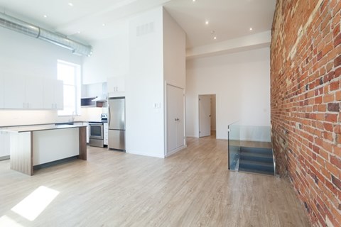 A kitchen with a white counter top and a brick wall.