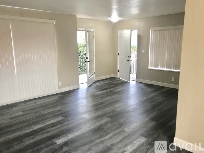 A room with wooden flooring and white walls.