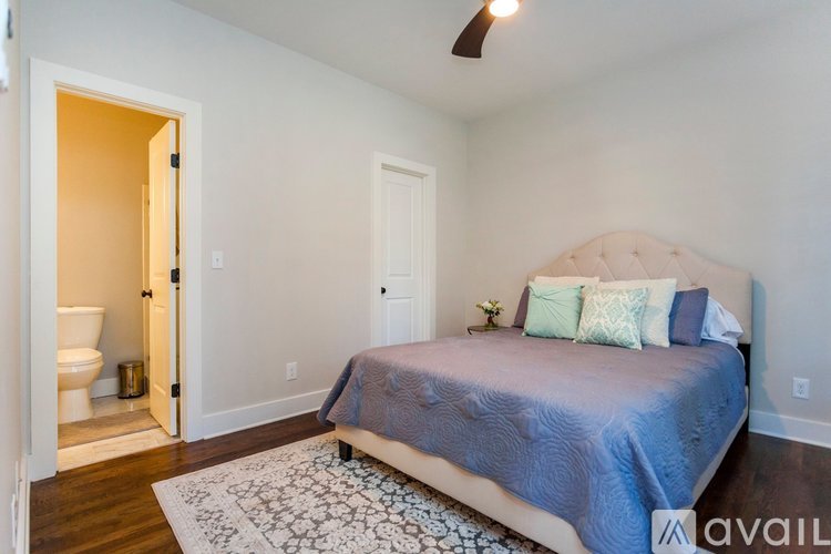 A bedroom with a bed, pillows, and a rug.