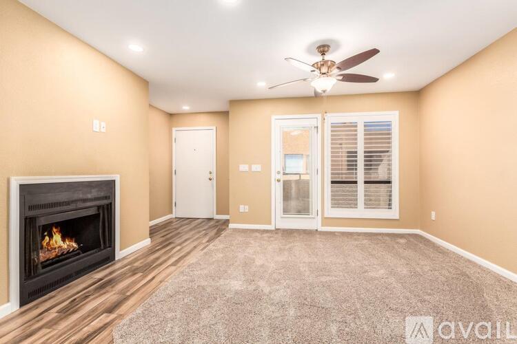 A living room with a fireplace and a fan on the ceiling.
