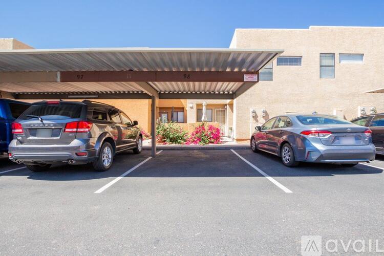 A parking lot with a building entrance and two cars parked in front.