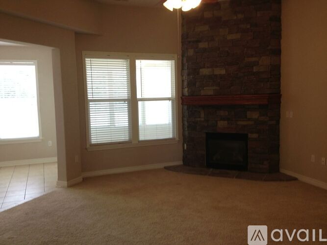 A living room with a fireplace and a window with blinds.