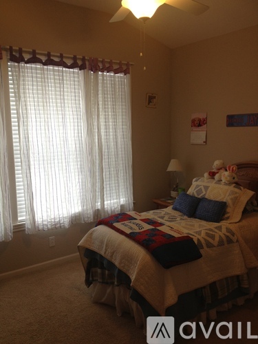 A bedroom with a bed, a ceiling fan, and a window with blinds.