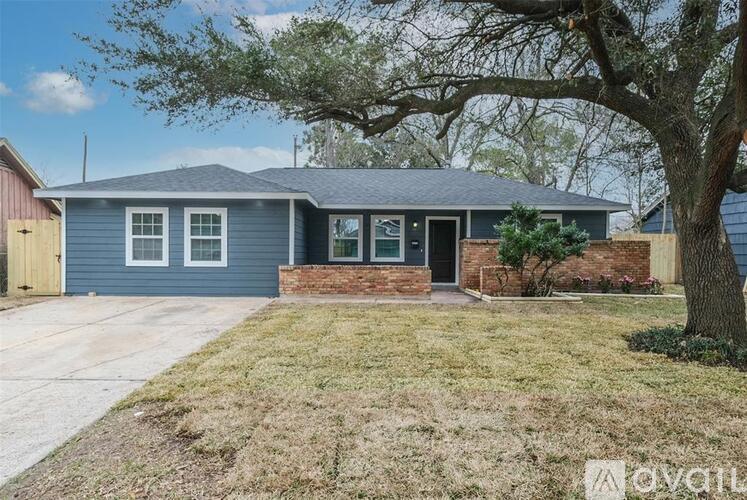 A house with a grey roof and a tree in front.