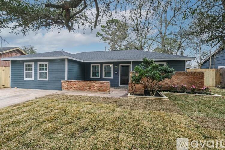 A house with a blue exterior and a brick wall in front.