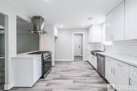 A modern kitchen with white cabinets and a wooden floor.