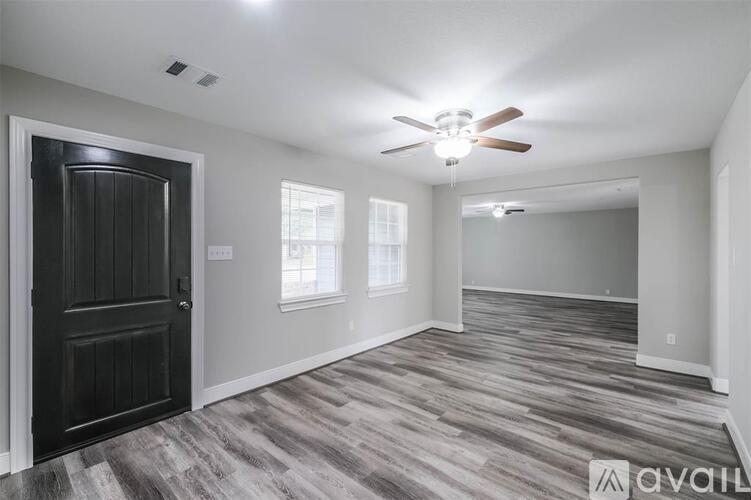 A spacious room with a ceiling fan and wooden flooring.