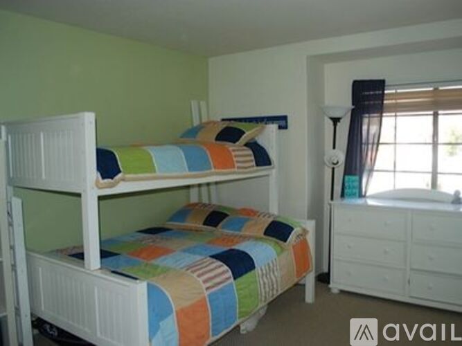 A bedroom with two bunk beds and a dresser.