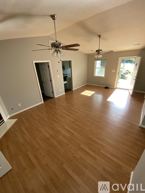 A room with wooden flooring and two ceiling fans.