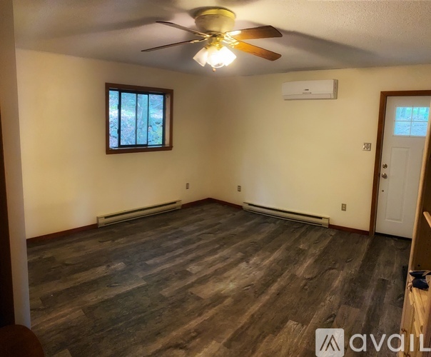 A room with a ceiling fan and a window with a view of trees outside.