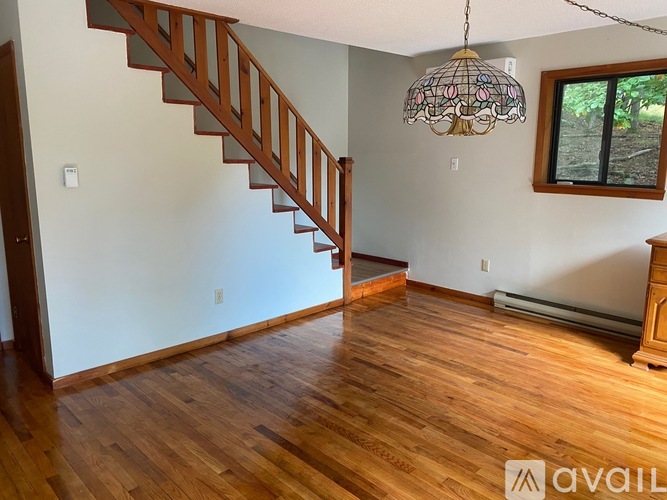 A wooden staircase with a chandelier in the middle of the room.