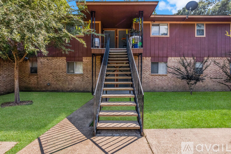 A house with a red exterior and a wooden staircase leading to the second floor.