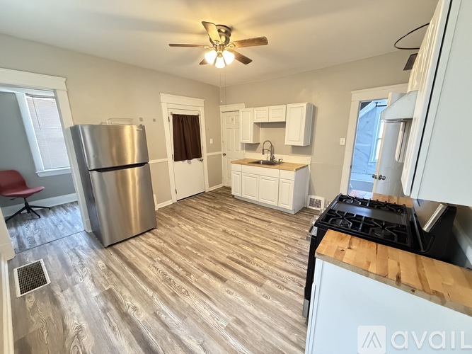 A kitchen with a refrigerator, stove, and a fan on the ceiling.